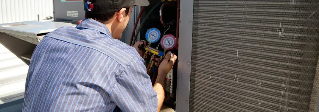 HVAC technician servicing a condenser unit in Fruitvale